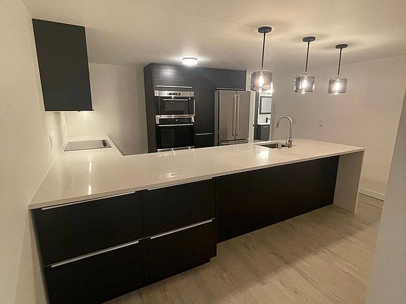 Kitchen has extra storage with room for 3 at the counter bar under pendant lights