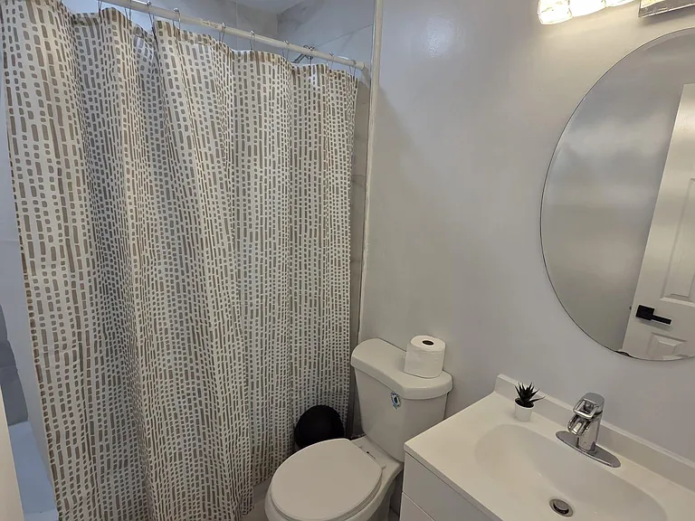 Full bathroom with shower/tub combo, modern vanity with storage, and a large wall mirror for daily routines.