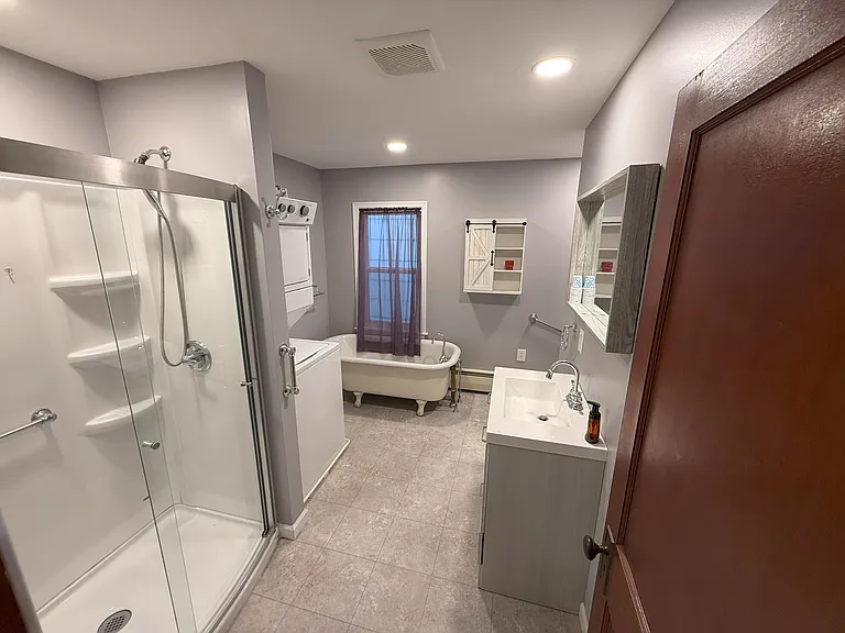Bathroom with walk in shower and soak tub. Washer and dryer combo unit.