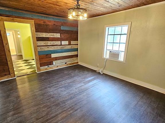 Living room with charming accent wall equipped with a remote controlled window unit and ceiling fan light fixture.