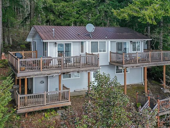 Drone shot of the rear of the home showing the 3 decks and staircase down to your private beach. >