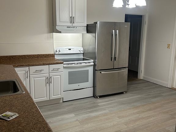 Kitchen with updated appliances and vinyl plank flooring. Photos taken at night.