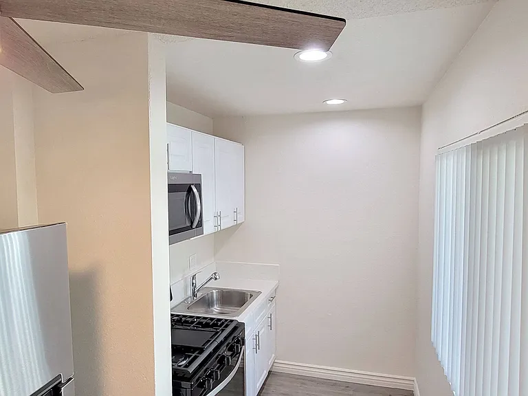 Kitchen with large window, ceiling fan and stainless steel appliances at Orlando Woods Apartments in El Cajon, California.