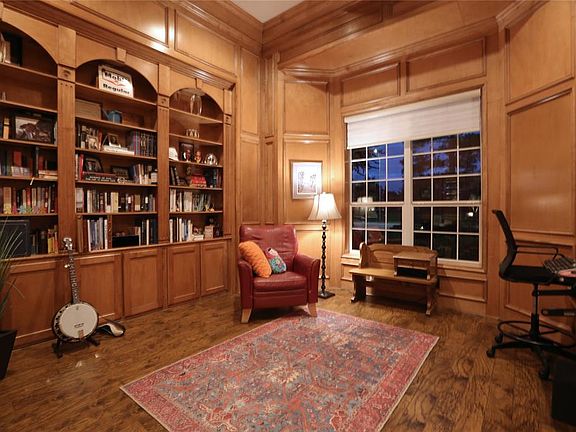 The elegant study with warm wood floors, paneling and molding is a comfortable space for work or relaxation.