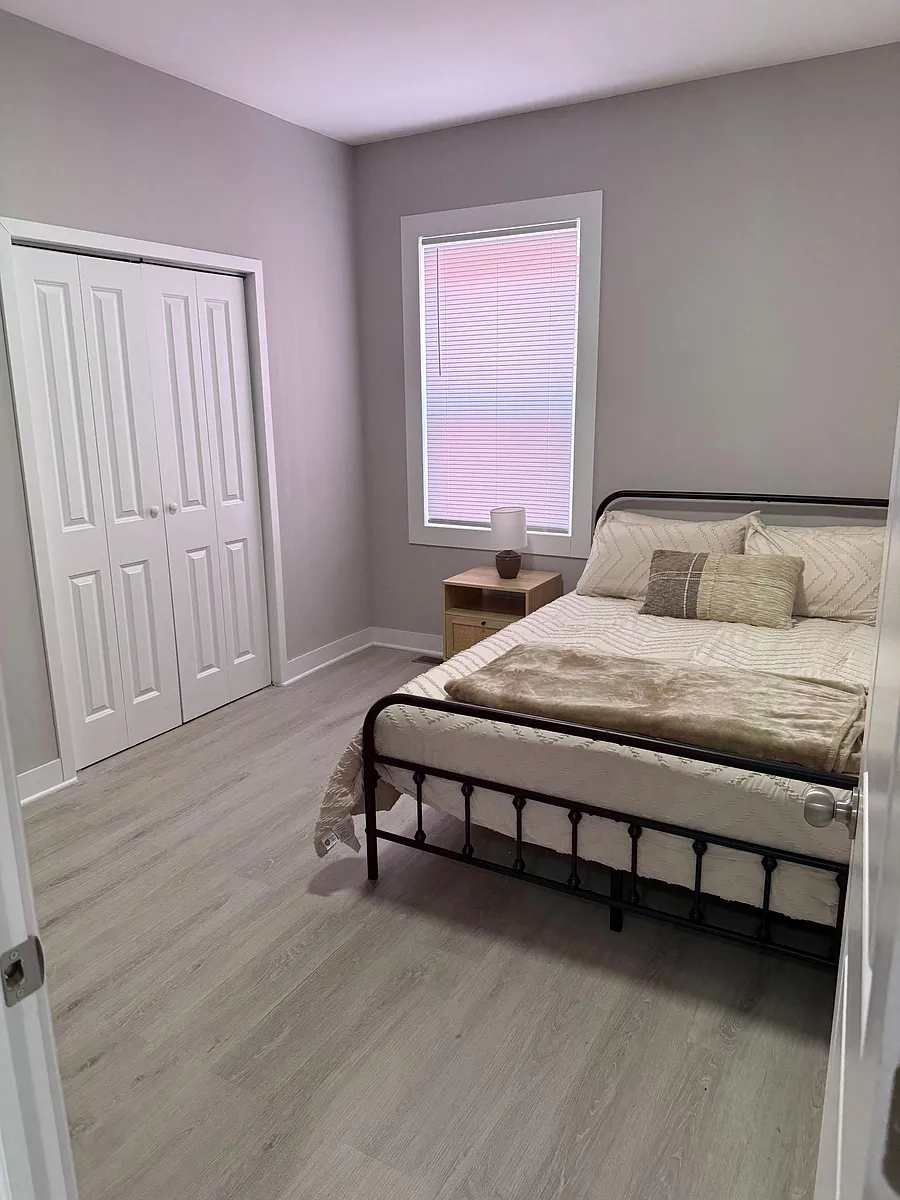 Photo 1 of 10 - E Maryland St - Indianapolis, IN Furnished bedroom with a queen bed, nightstand, spacious double closet, and a window with blinds for privacy. - E Maryland St