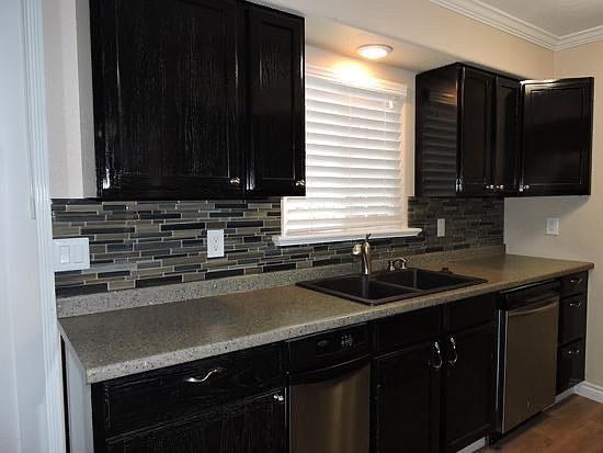 Stunning black cabinet kitchen with tile blacksplash, corian counters and stainless steel appliances.