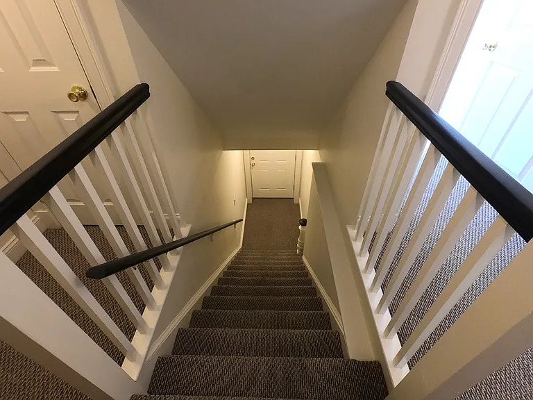 Staircase going down from the shared hallway to the front entrance.