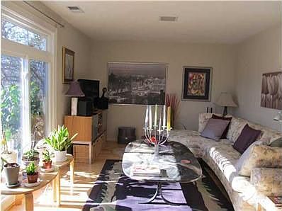 Family room with hardwood flooring and large windows that look out onto patio.
