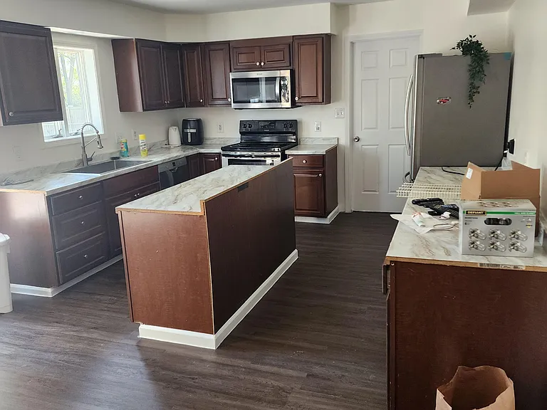 Kitchen with ample cabinet storage, stone-look counters, and a full appliance package including a microwave and fridge.