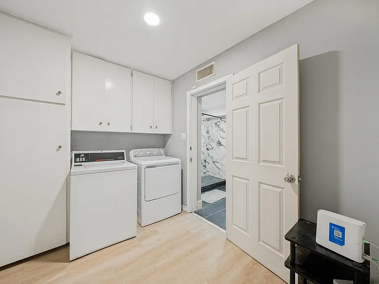 Dedicated laundry area with full-size washer and dryer, plus overhead cabinetry for organized household storage.