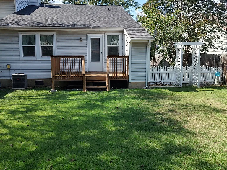 Grassy back yard w/ shade trees, totally fenced in for your privacy.