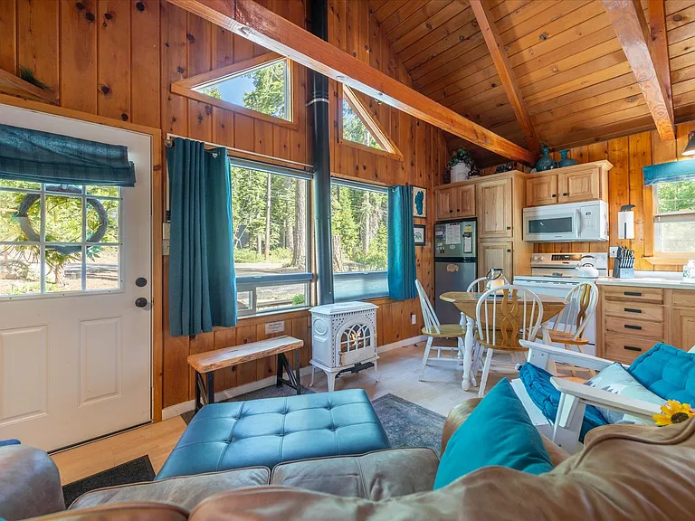 Main living area, dining, kitchen with vaulted ceilings, knotty pine wood accents and gas stove.