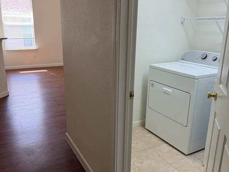 View from hallway showing utility room and living room in background.