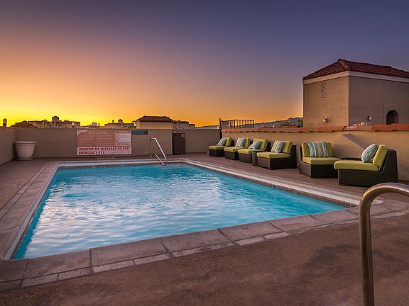 Rooftop swimming pool at sunset, surrounded by lounge chairs.