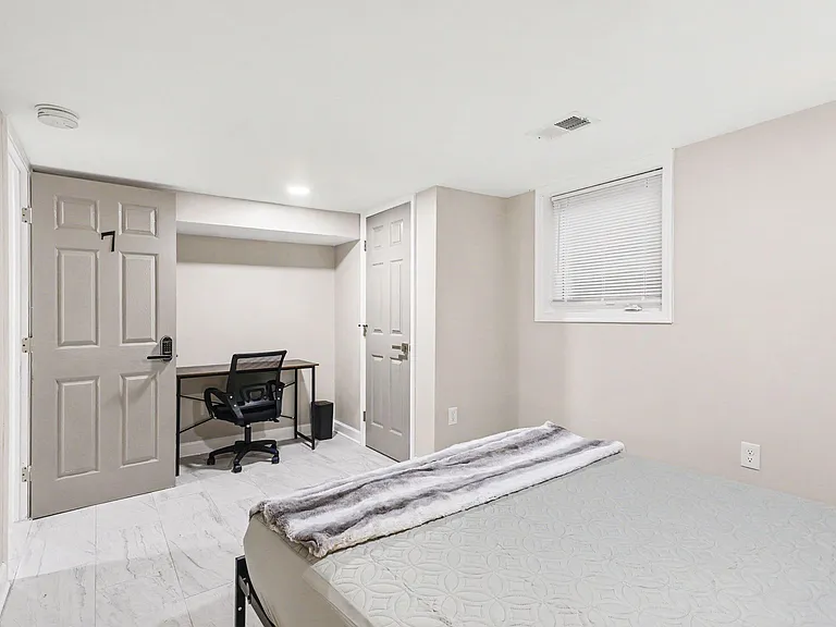 Private bedroom with durable tile flooring, a window with blinds, and a dedicated desk areaideal for work or study.