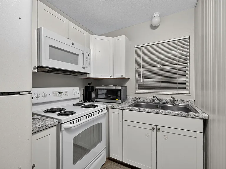 Efficient kitchen with ample cabinetry, laminate counters, double-basin sink, and a full appliance set for everyday cooking.