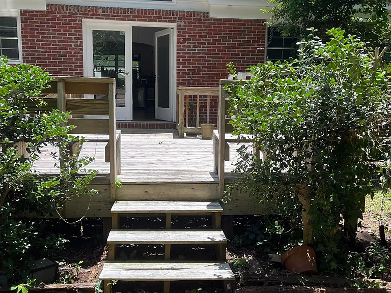 in the backyard looking back at the house. deck is multi - level with grill.