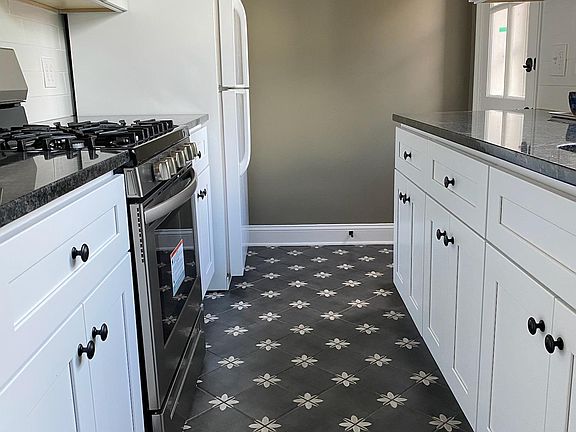 Your newly renovated kitchen looking towards the back door. We absolutely LOVE this tile floor! (Hope you will too.) New stainless fridge with ice maker installed July 2022, not pictured.