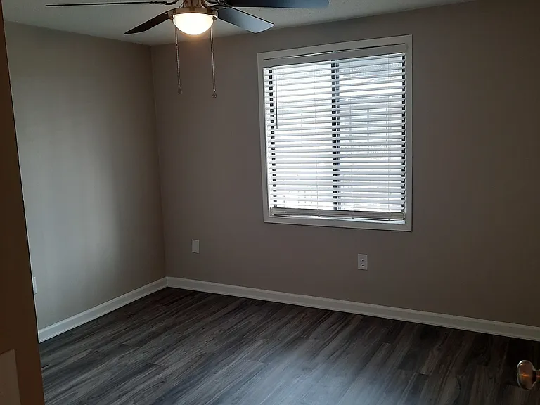1 bedroom living room with large front window and VCT flooring in light gray