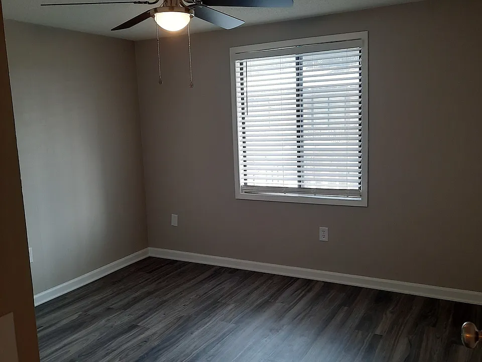 1 bedroom living room with large front window and VCT flooring in light gray