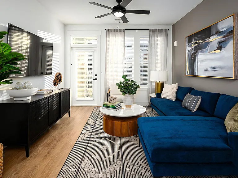Living room with blue sectional sofa, round coffee table, and wall-mounted TV