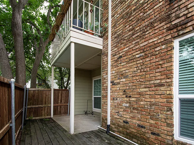 Exterior brick facade with white-framed windows featuring horizontal blinds
