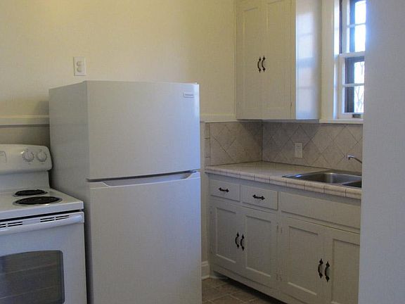 Kitchen view from dining room swinging door. Updated kitchen with new tile counter, flooring. dishwasher. New refrigerator.