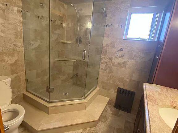 Spacious tiled bathroom featuring glass-enclosed shower and contemporary finishes