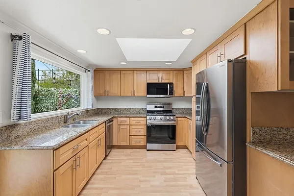 Kitchen with large skylight, all stainless steel appliances.