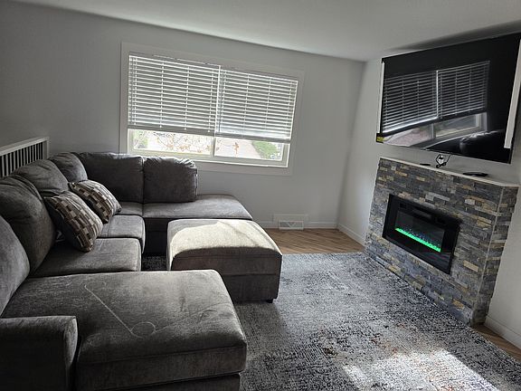 Beautiful living room with 75 Inch adjustable smart TV with electronic fireplace.