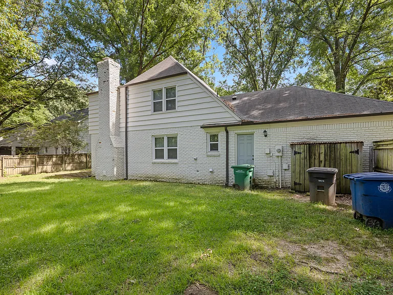 Rear view of the home showcasing a lush green lawn, brick chimney, and direct backyard access _ great for outdoor entertaining.