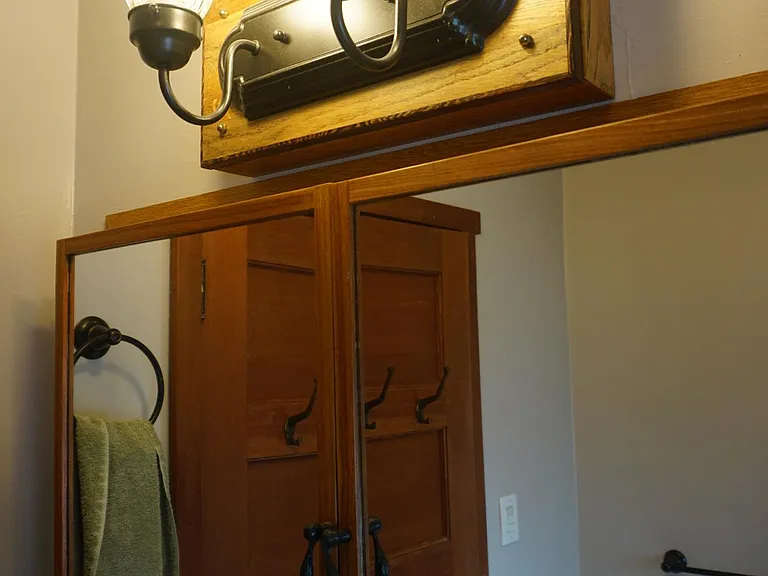 This is a photo of the bathroom, which has a reflection (medicine cabinet) of the door into the bathroom and the hand towel and full towel rack as well as the laundry chute door.