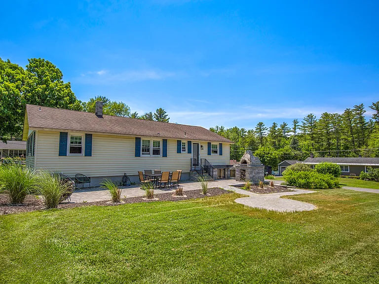 View of house, patio pizza oven & grill from back lawn