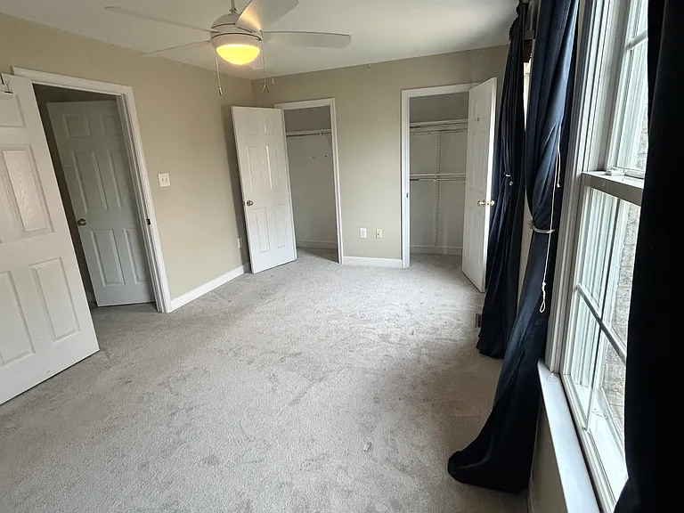 Back facing bedroom with twin closets, two light-filled windows, fan, and attached full bathroom. This is a large bedroom and can easily have a shared home office. Carpet is two years old.