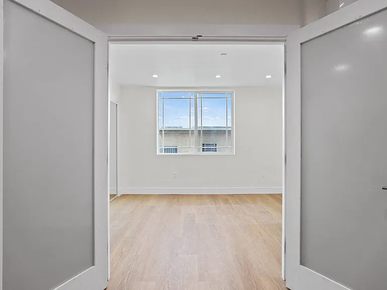 Double-Doors Leading to Bedroom Space with Window, Recessed Lighting, and Vinyl Flooring