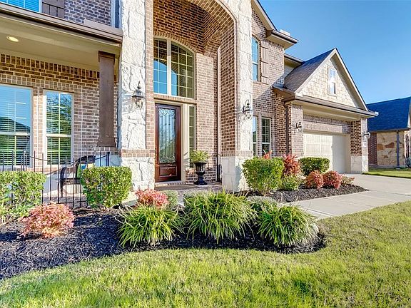 The house has tall entry and covered front porch with immaculate landscaping.