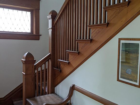 Front entry with original leaded glass windows, staircase and storage entry bench.