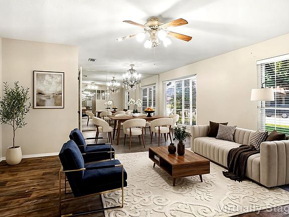 Living area with wood flooring & natural lighting opens to formal dining area...