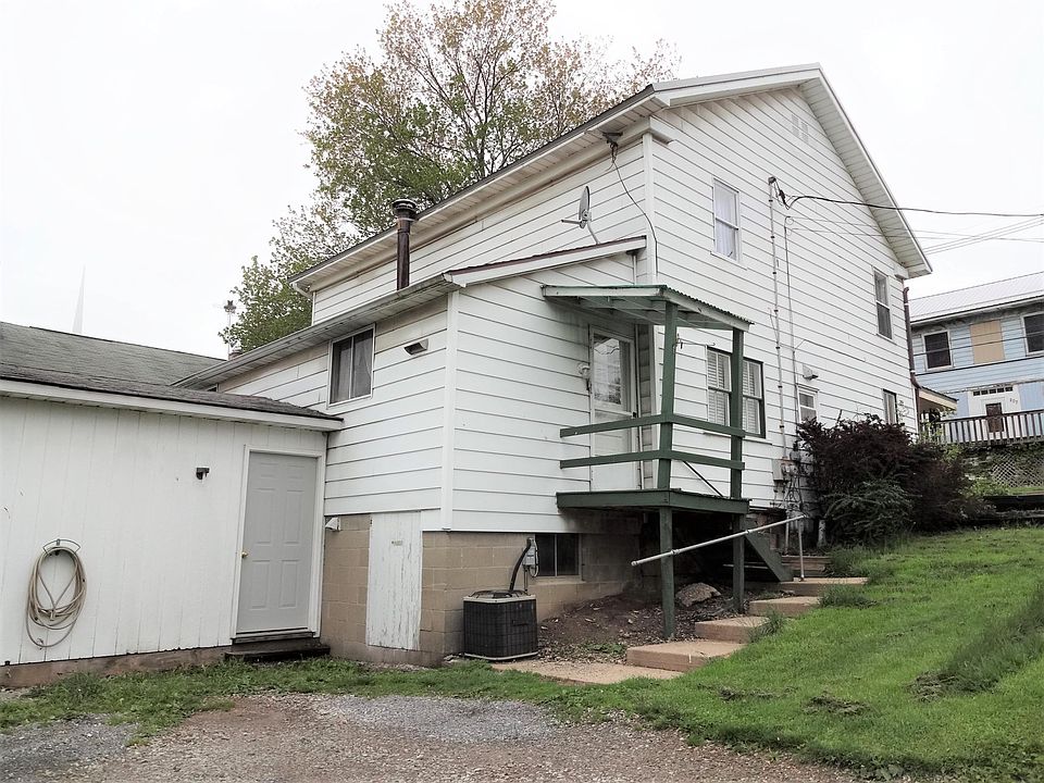 Side of view of house, small porch, workshop/storage area, and off-street parking