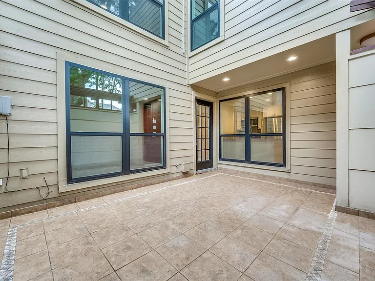 Tiled patio area with neutral-toned siding and multiple large windows