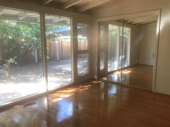 Master bedroom with wood floor, a mirrored closet and a door to the private backyard.