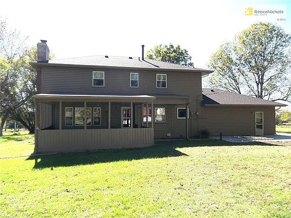 Back of home showing trees, large yard and covered deck.