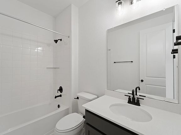 The private bath features tile flooring, white cabinetry and light countertops and a shower tub comb