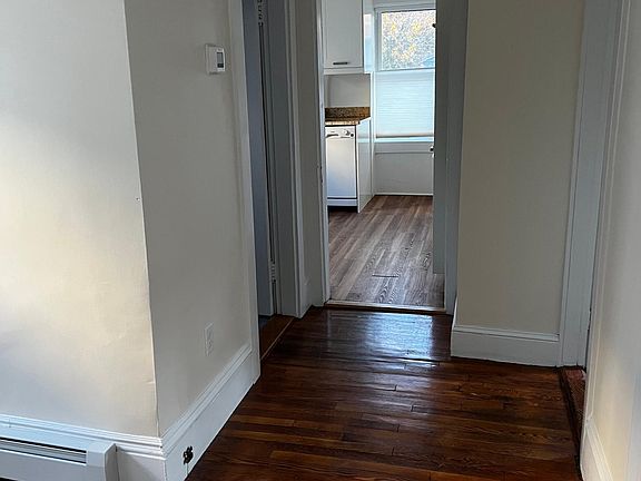 View from front hall (standing outside living room) to kitchen. Near right is door to small bedroom (study) far right is door to larger bedroom, bathroom is on left, kitchen straight ahead.