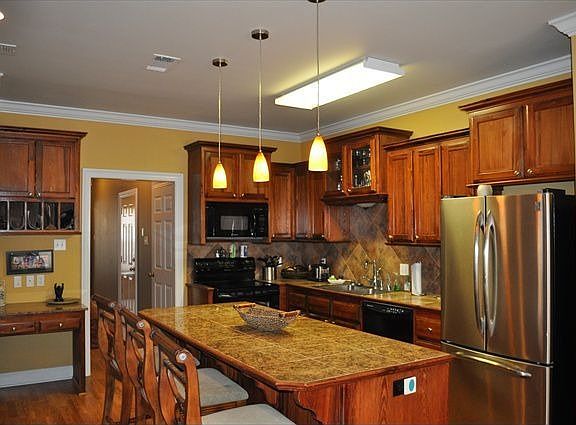 Kitchen has island with granite tile countertops