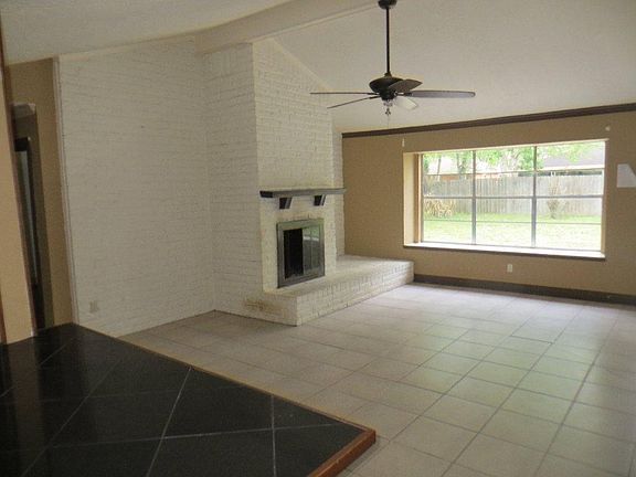 Spacious living area with tile floors, ceiling fan, fireplace
