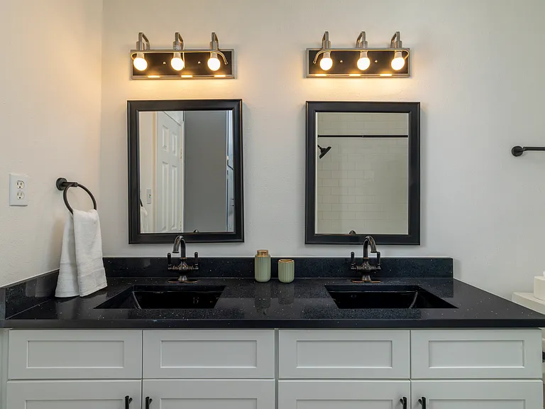 Full bathroom with double sinks and shower-tub combo attached to bedroom 1.