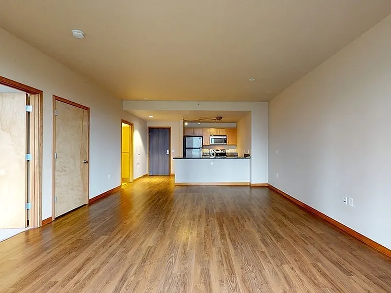 Gourmet kitchen with stainless steel appliances, dining and living room with wood-style flooring.