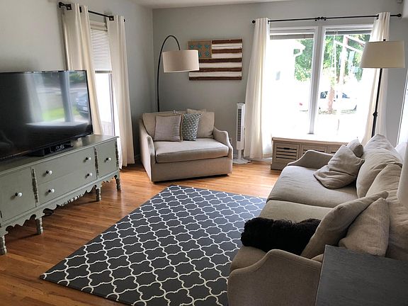 Sunny living room has view of front driveway and side patio.