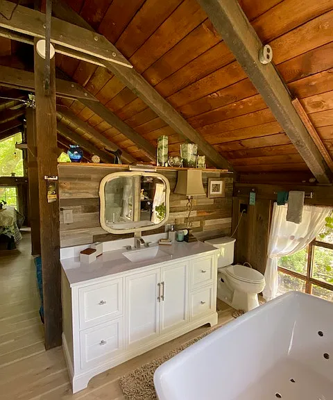 beyond the bathroom sink is the sitting room, open ceilings throughout.